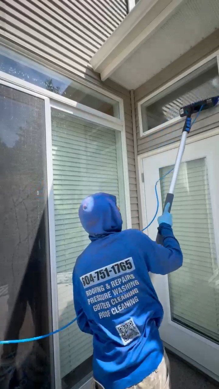 All Canadian Home Services window cleaner cleaning a transom window above a patio door
