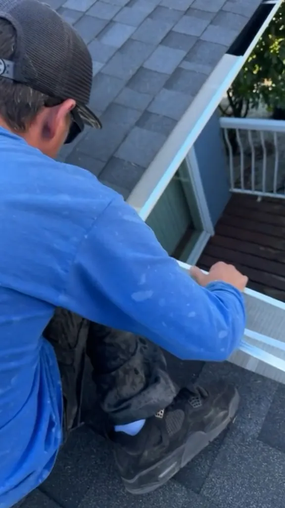 Technician pressing a gutter guard into place along the gutter above a deck