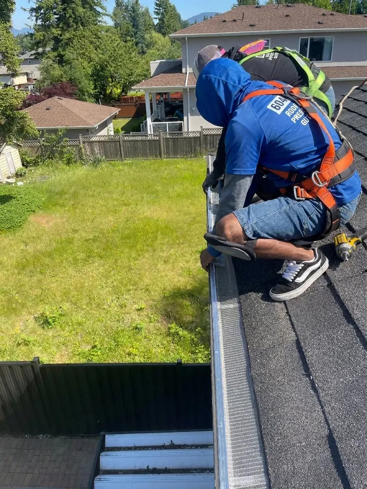 Fitting small-hole gutter guards along a roof edge in Surrey BC