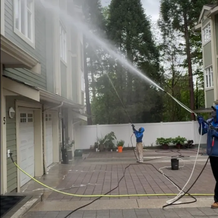 Two-person crew washing the exterior of a townhouse block from the shared drive aisle, Greater Vancouver
