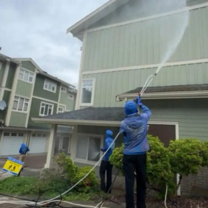 Two All Canadian Home Services crew soft washing the upper storey of a green townhouse block in Greater Vancouver