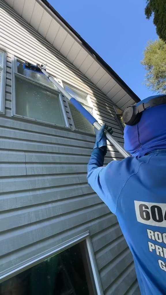 Upper-storey window cleaned from the ground with an extension pole, no ladder against the house